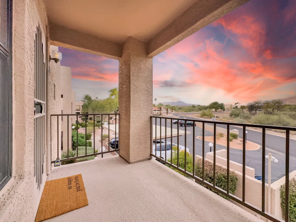 A peaceful balcony scene overlooking a vast landscape, with a sturdy railing framing the view of a glowing sunset sky and distant terrain. The area is tranquil, ideal for sipping coffee or unwinding after a day exploring the outdoors.