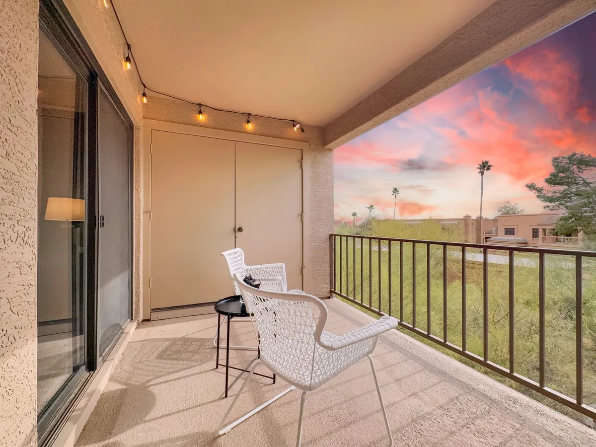 A serene patio scene featuring decorative string lights, white chairs, and sweeping landscape views—an ideal setting for quiet mornings or sunset relaxation. The inviting setup suggests privacy and tranquility, perfect for unwinding after an active day.
