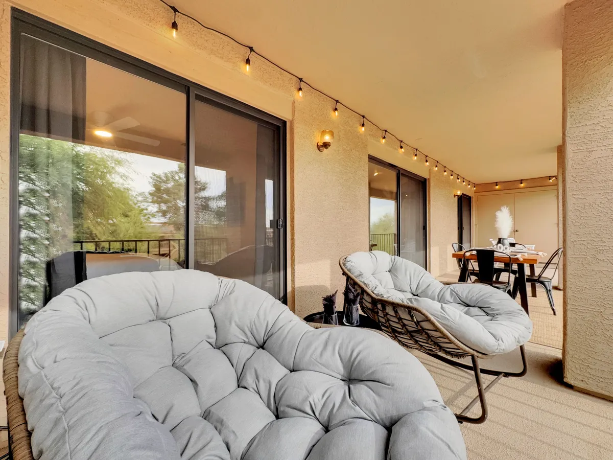 A stylish balcony setup with comfortable seating, a dining table, and string lights. The outdoor area feels like an extension of the interior, ideal for al fresco dining and enjoying panoramic mountain views.