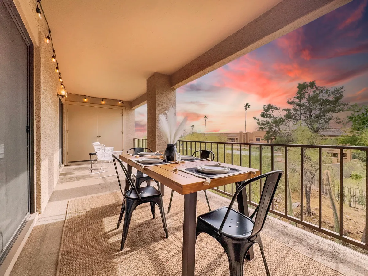 An outdoor dining table and chairs set against a scenic outdoor view with a decorative plant centerpiece. The setting is tranquil, inviting guests to enjoy meals while watching the sunset.